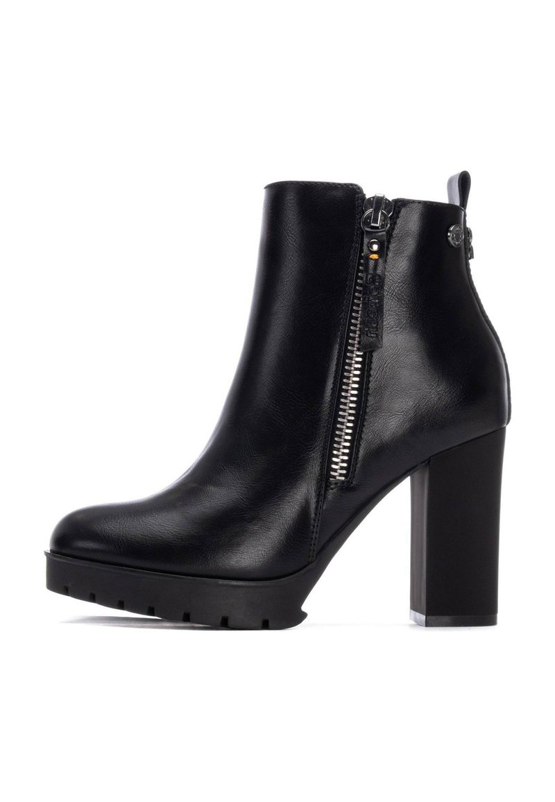 Botas de tobillo de cuero negro con un tacón alto y grueso, cremallera lateral y suela texturizada, con un acabado suave y mínimos acentos de herrajes.