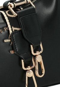 Borsa nera con una texture in pelle liscia, caratterizzata da ferrature dorate e una tracolla decorativa con un motivo intrecciato in nero e beige.