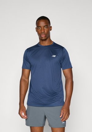 T-shirt de sport bleu marine à manches courtes avec une finition texturée, portant un petit logo blanc sur la poitrine gauche, associé à un short gris.