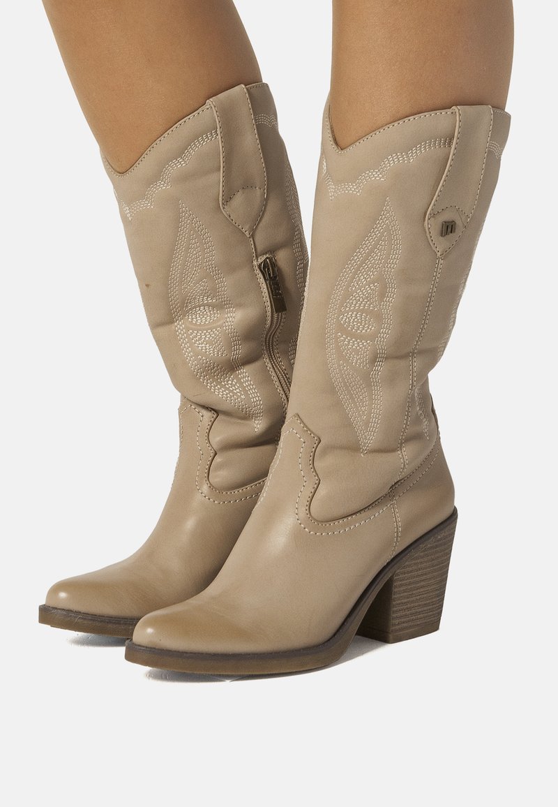 Stivali da cowboy in pelle beige con cuciture decorative, punta appuntita e tacco a blocco. Presentano una cerniera laterale per una facile indossabilità.
