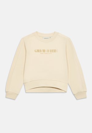 Světle béžová mikina s kulatým výstřihem a dlouhými rukávy, s nápisem "Calvin Klein New York City" ve zlaté barvě na přední straně.