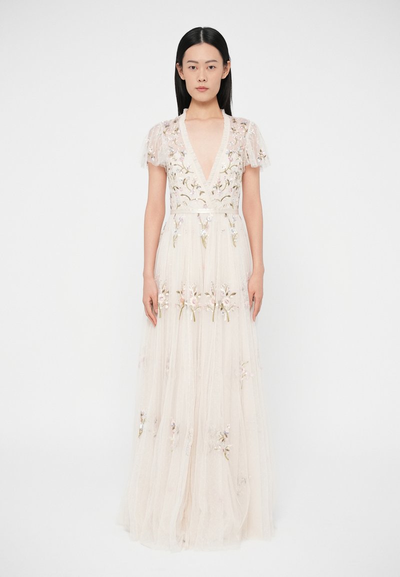Dlhé krémové šaty z priesvitnej látky, zdobené kvetinovou výšivkou a krátkymi volánovými rukávmi. Hlboký výstrih do V pridáva eleganciu.