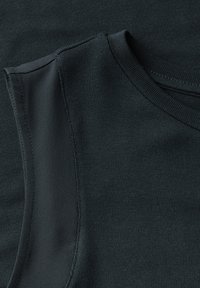 Mörkgrön ärmlös topp med ribbad textur. Har en rundad halsringning och subtila axeldetaljer. Materialet verkar mjukt och stretchigt.