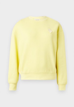Geel sweatshirt van gestructureerde stof, met een ronde halslijn, lange mouwen en een klein diamantvormig accent op de borst.