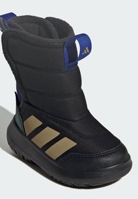 Crni atletski čizmi s teksturiranim gornjim dijelom, zlatnim trostrukim uzorkom, podstavljenim okovratnikom i gumenim potplatom. Ima plavi povlačni trak.