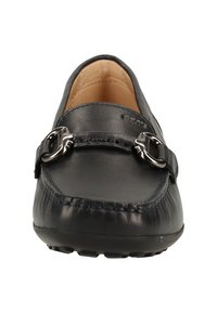 Mocassin en cuir noir avec détail en métal argenté sur l'avant et coutures visibles sur l'embout arrondi.