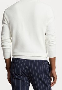 Vit texturerad tröja med ribbade ärmslut och nederkant, kombinerad med marinblå randiga byxor med en subtil fickdetalj.