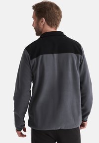 Grau Fleecejacke mit schwarzem Kragen und Schulterbesatz, langärmlig und mit lässiger Passform. Weiche Textur und minimale Details.