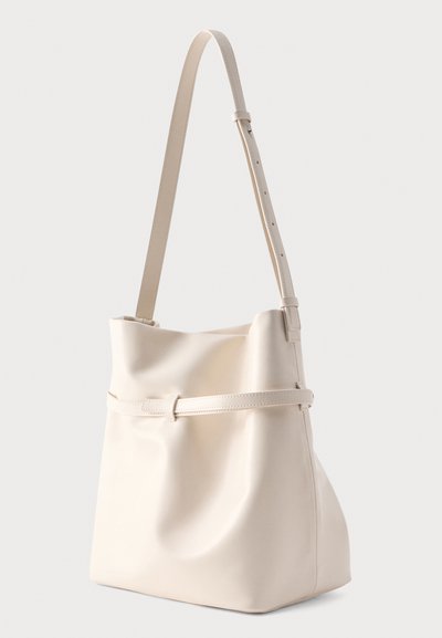 Sac d'épaule en cuir couleur crème avec bandoulière réglable et détail de ceinture horizontale autour du milieu, forme structurée mais souple.