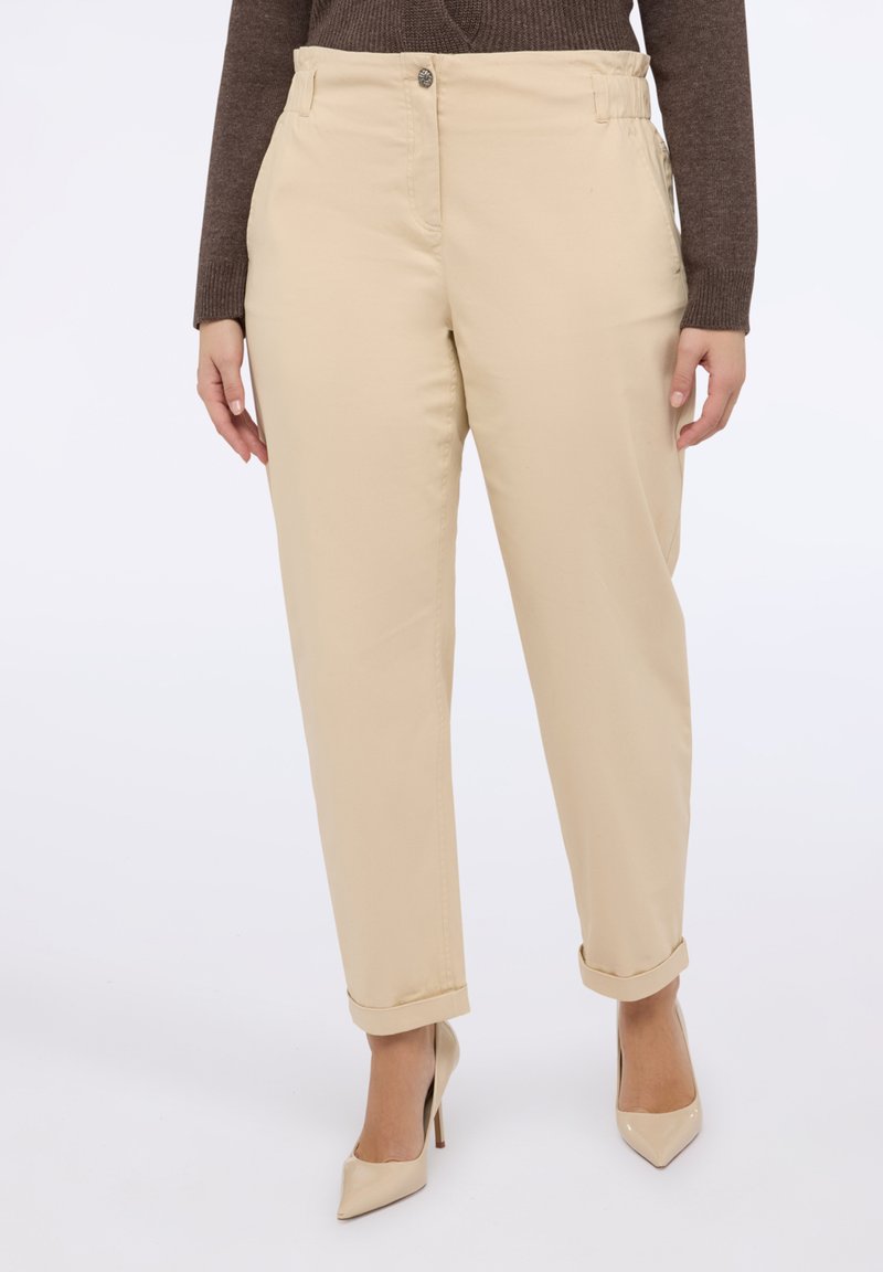 Béžové bavlněné kalhoty s tapered střihem, s knoflíkovým zapínáním, bočními kapsami a ohrnutými manžetami. Hladká textura a neutrální barva.