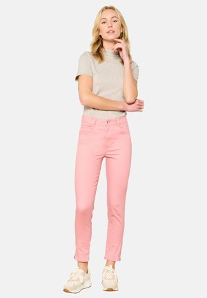 Haut gris clair à manches courtes associé à un jean slim-fit rose vif, avec un ourlet court et une texture subtile, complété par des baskets.