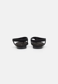Mustad sandaalid tekstuuriga kummirihmaga ja lame talla. Kujundus on minimalistlik ja avatud seljaga, mis tagab mugava selga panemise.