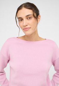 Helles rosa Rundhals- Sweatshirt mit einer weichen Textur und lässiger Passform. Die Ärmel sind leicht abgesenkt und das Design ist einfach und klar.