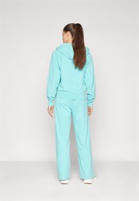 Ανοιχτό μπλε σετ φούτερ και παντελόνι φόρμας, με χαλαρή σχεδίαση, ρυθμιζόμενη κουκούλα και άνετη εφαρμογή, φτιαγμένο από μαλακό ύφασμα.