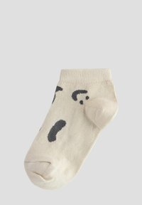 Chaussette beige jusqu'à la cheville avec des taches abstraites noires, texture tricotée, bout rond et poignet côtelé. Convient pour une tenue décontractée.