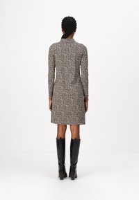 Leopardenprint-Kleid mit langen Ärmeln, figurnahem Design und geradem Schnitt. Getragen mit schwarzen kniehohen Stiefeln im Krokodil-Look.