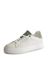 Baskets basses blanches avec lacets blancs, semelle épaisse, languette et col de talon en daim vert olive, inclinées vers la gauche sur fond blanc.