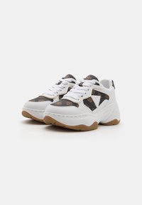 White sneakers with a leather and patterned fabric upper, featuring a textured gum sole and prominent lacing system. Distinctive logo detail.