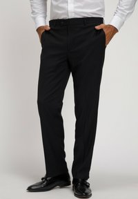Pantaloni neri da abito con una vestibilità slim, vita media e una sottile texture, abbinati a scarpe da abito nere lucide.