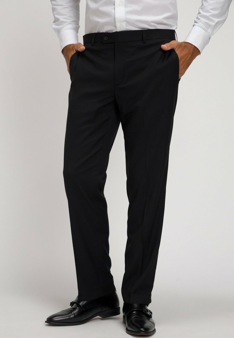 Pantaloni neri da abito con una vestibilità slim, vita media e una sottile texture, abbinati a scarpe da abito nere lucide.