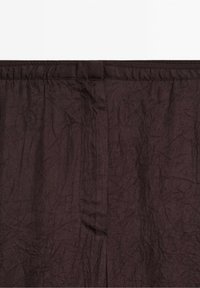 Tissu froissé marron foncé avec une ceinture élastique froncée et une couture centrale.