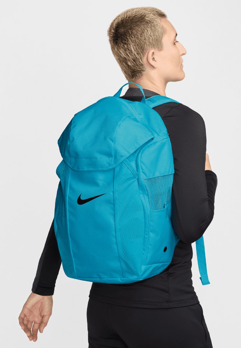 Türkiz Nike hátizsák lekerekített tetejével, párnázott vállpántjaival, hálós oldalzsebével és a oldalán jól látható fekete swoosh logójával.