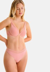 Soutien-gorge rose pâle avec un décolleté en V profond, orné d'accents en dentelle texturée et de bretelles ajustables. Culotte en bikini sans coutures assortie avec une bande en dentelle.