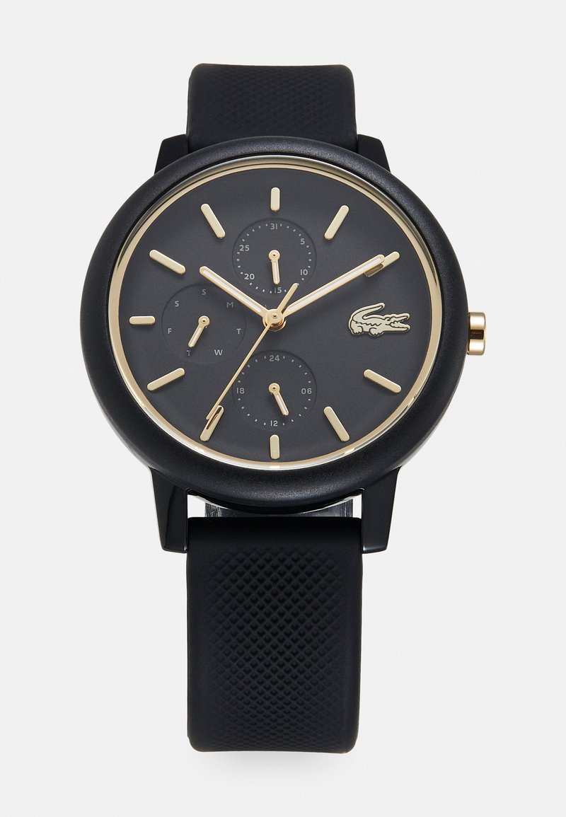 Reloj con correa de silicona negra, esfera redonda negra, marcadores de horas dorados, tres subesferas y un logotipo dorado de cocodrilo.