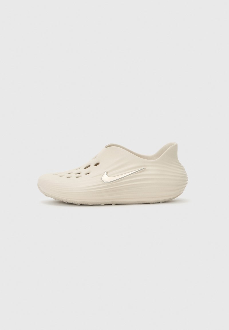 Beige slip-on παπούτσι με λείο φινίρισμα, που διαθέτει αεραγωγούς, καμπυλωτή σιλουέτα και μεταλλικό λογότυπο στο πλάι.