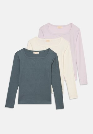 Trois hauts à manches longues en tricot côtelé avec encolure carrée en gris foncé, blanc cassé et lavande claire, posés à plat et superposés sur fond blanc.