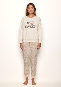 Light beige sweatshirt with "SO SWEET" text and bear graphic, paired with light brown leopard print jogger pants. Soft fabric, relaxed fit.