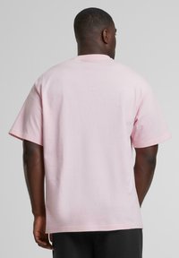 Short-sleeve, crew-neck t-shirt in light pink cotton. Features a relaxed fit with a smooth texture and no visible patterns or accents.