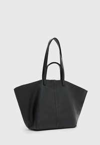 Sac cabas en cuir noir avec une forme triangulaire large et deux longues poignées. La surface a une finition texturée et un détail de couture central.