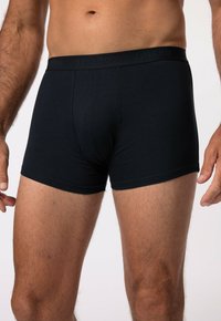 Boxers pour hommes noirs fabriqués à partir d'un tissu lisse. Présentent une taille élastique douce avec le nom de la marque en relief. La coupe est ajustée et confortable.