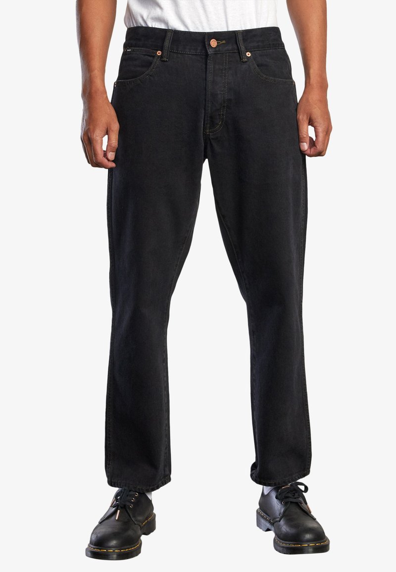 Jeans de mezclilla negra con corte recto, que cuentan con cinco bolsillos, herrajes de cobre y costuras en contraste. Combinados con zapatos negros de cordones.