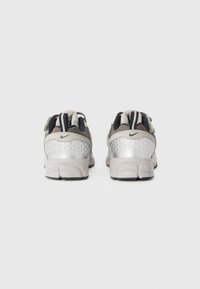 Nike-Sneaker mit reflektierendem silbernen Fersenpaneel, grauem Mesh-Obermaterial, schwarzen Akzenten und einer strukturierten Sohle.
