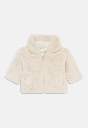 Veste courte en fausse fourrure couleur crème avec un grand col, une fermeture éclair frontale et deux poches latérales.