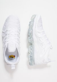 White athletic shoes with a smooth synthetic upper, clear air cushioning sole, thick white laces, and a textured pattern along the sides.