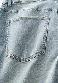 Világoskék farmernadrág, egyetlen hátsó zsebbel, látható varrási részletekkel és sima felülettel.