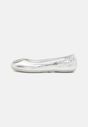 Silberne Ballerinas mit glänzender Oberfläche, runder Zehenpartie und dekorativem Emblem auf der Oberseite. Elastischer Rand am Öffnungsbereich für Flexibilität.