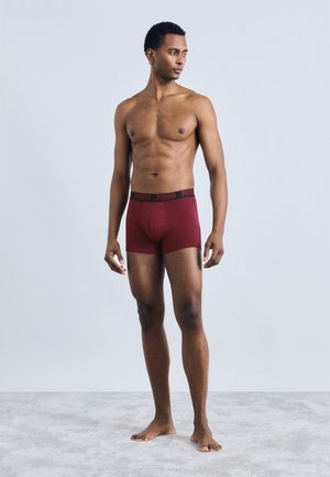Maroon boxer briefs with a black elastic waistband featuring the "PUMA" logo, shown on a standing male model against a plain background.