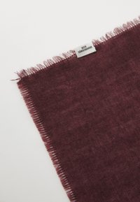 Burgundia sall, mis on valmistatud pehmest kangast ja millel on narmastega ääred; silt näitab kaubamärki. Tekstuur näeb välja sile ja kerge läikega.