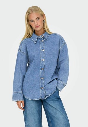 Lys blå denimskjorte med krave, frontknapper og lange ærmer. Blød tekstur med en afslappet pasform og rundet kant.