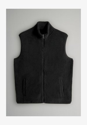 Chaleco de forro polar negro con cuello alto, cremallera frontal y dos bolsillos laterales. Textura suave y sin mangas, diseñado para warmth y comodidad.