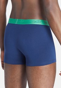 Boxer briefs blu navy realizzati in morbido tessuto, con una cintura elastica verde con logo in rilievo e un design aderente.