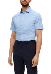 Hellblaues Kurzarmhemd mit button-down Kragen, glatter Textur und weißen Knöpfen, kombiniert mit dunklen Hosen.