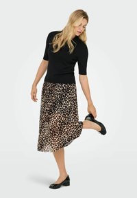 Melnas īsām piedurknēm pieguļošas džemperis, apvienots ar plūstošu dzīvnieku raksta midi svārku. Modelis valkā melnas balerīnas kurpes, izceļot svārku rakstu.