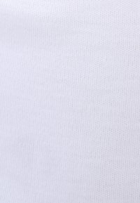 Tessuto bianco a righe con un aspetto texturizzato e lavorato a maglia. Il materiale è liscio e morbido, uniforme nel colore senza motivi o accenti.