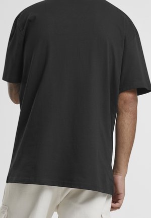 Czarny bawełniany t-shirt z krótkim rękawem o luźnym kroju, charakteryzujący się prostą, gładką fakturą bez widocznych grafik ani ozdób.