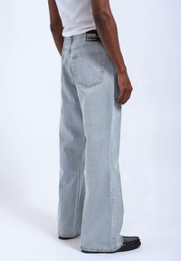 Jasnoniebieskie jeansy o szerokich nogawkach, wykonane z denimu, z wysokim stanem, pięcioma kieszeniami i czarną metką z logo z tyłu.